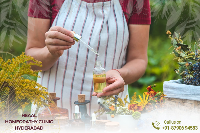 Homeopathic practitioner at HEAAL Homeopathy Clinic in Hyderabad preparing herbal tinctures with fresh plants, showcasing the personalized natural treatments offered, contact information included.