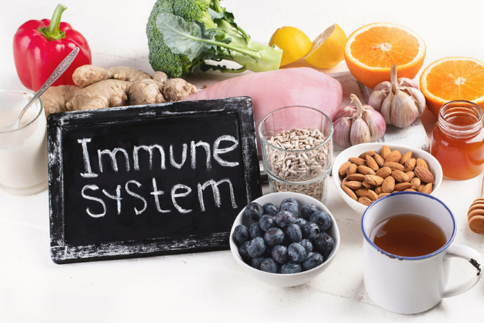 Variety of immune-boosting foods including fresh fruits, vegetables, nuts, and honey, with a chalkboard reading 'Immune System', promoting natural health and wellness at HEAAL Homeopathy Clinic in Hyderabad.