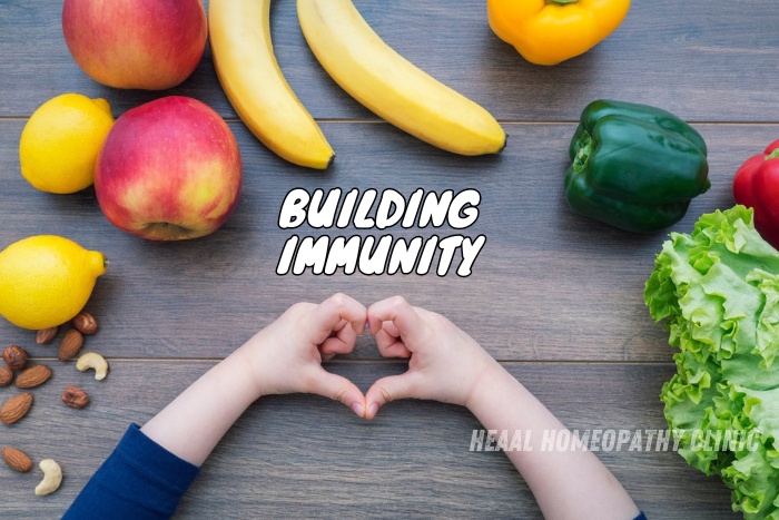 HEAAL Homeopathy Clinic in Chanda Nagar, Hyderabad, highlights the importance of building immunity naturally with a nutritious diet, featuring an array of fruits, vegetables, and nuts laid out on a wooden table, encouraging healthy living through homeopathic solutions
